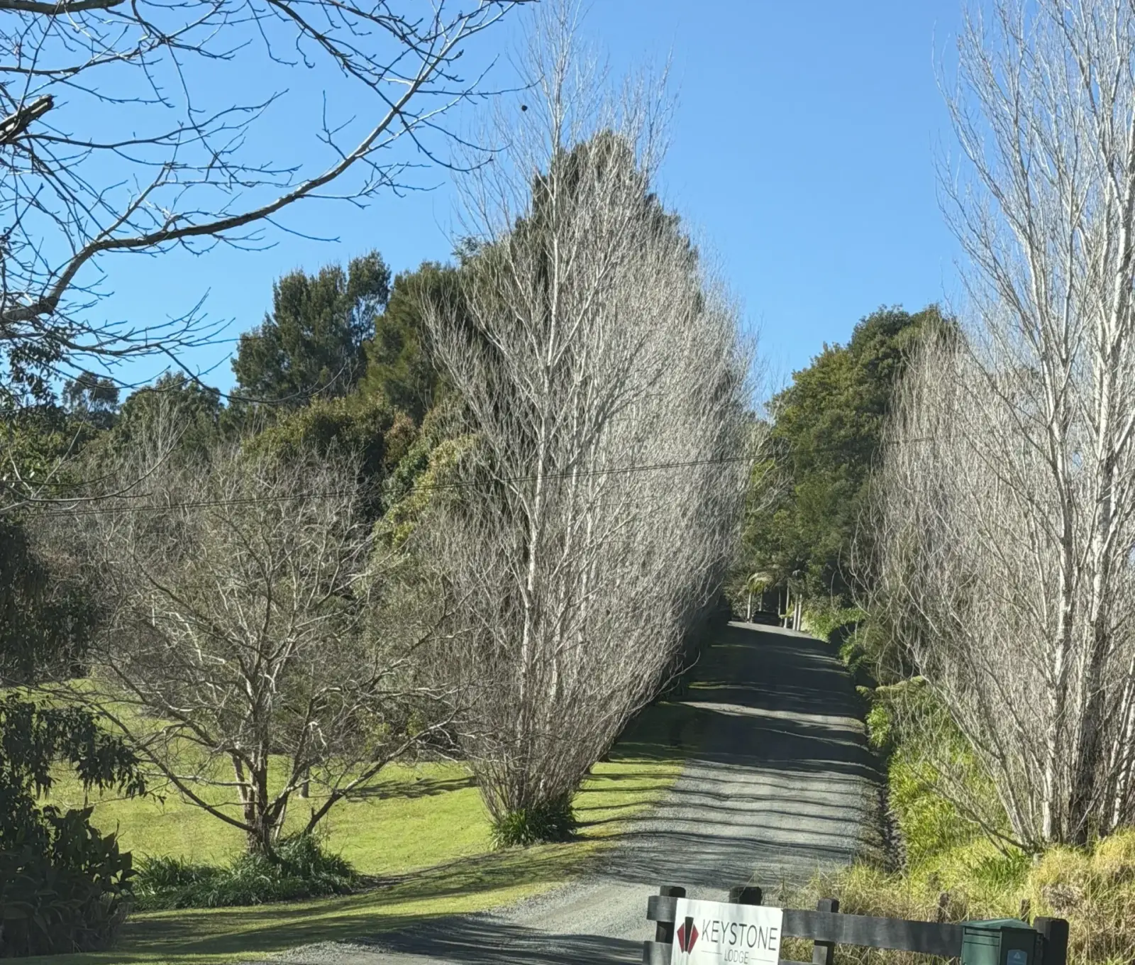The gravel driveway and wooden gate with the Keystone Lodge sign under a clear blue sky