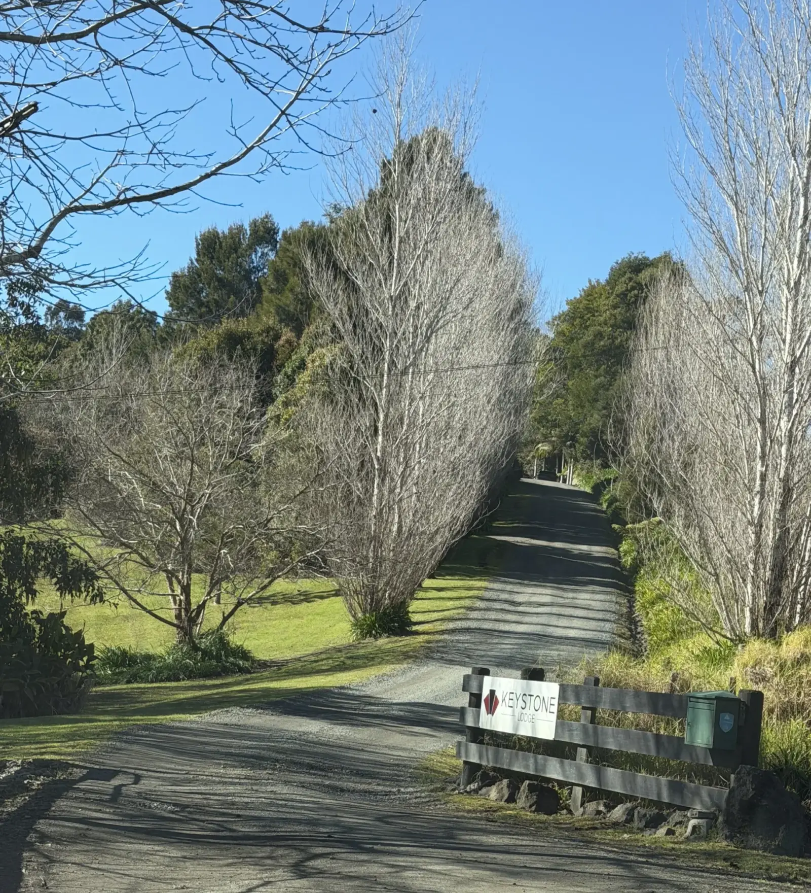 The gravel driveway and wooden gate with the Keystone Lodge sign under a clear blue sky