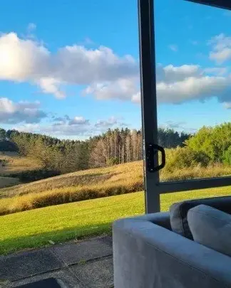 Grassy hills and trees seen through the large window of the therapy room at Keystone Lodge