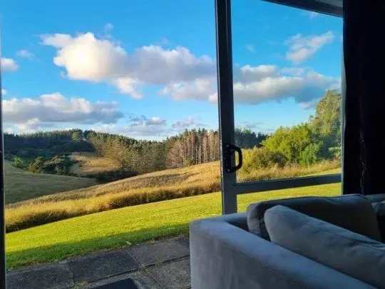 Grassy hills and trees seen through the large window of the therapy room at Keystone Lodge