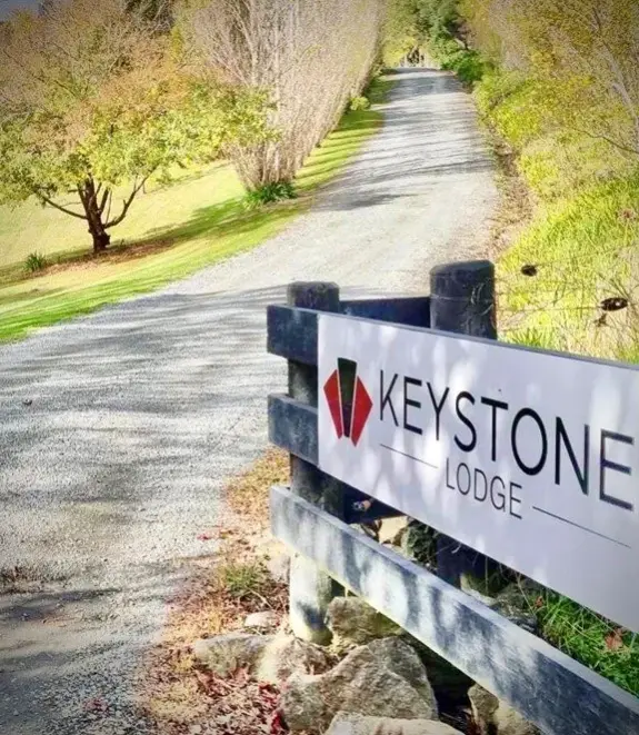 The gravel driveway and Keystone Lodge sign on the black wooden fence at the entrance.