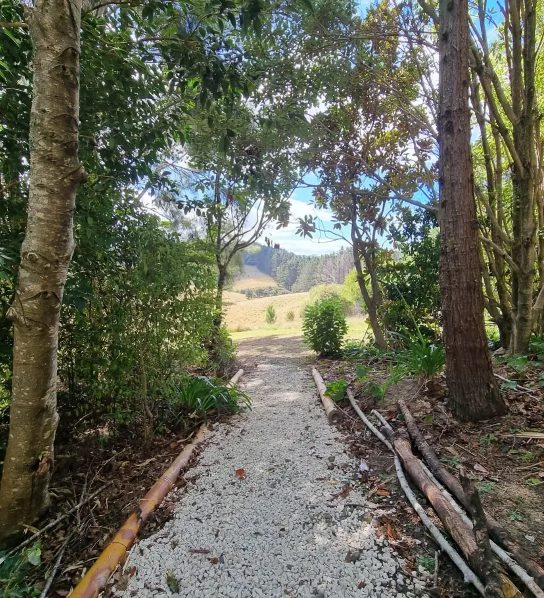 A gravel path through lush green trees leading to an open field at Keystone Lodge.
