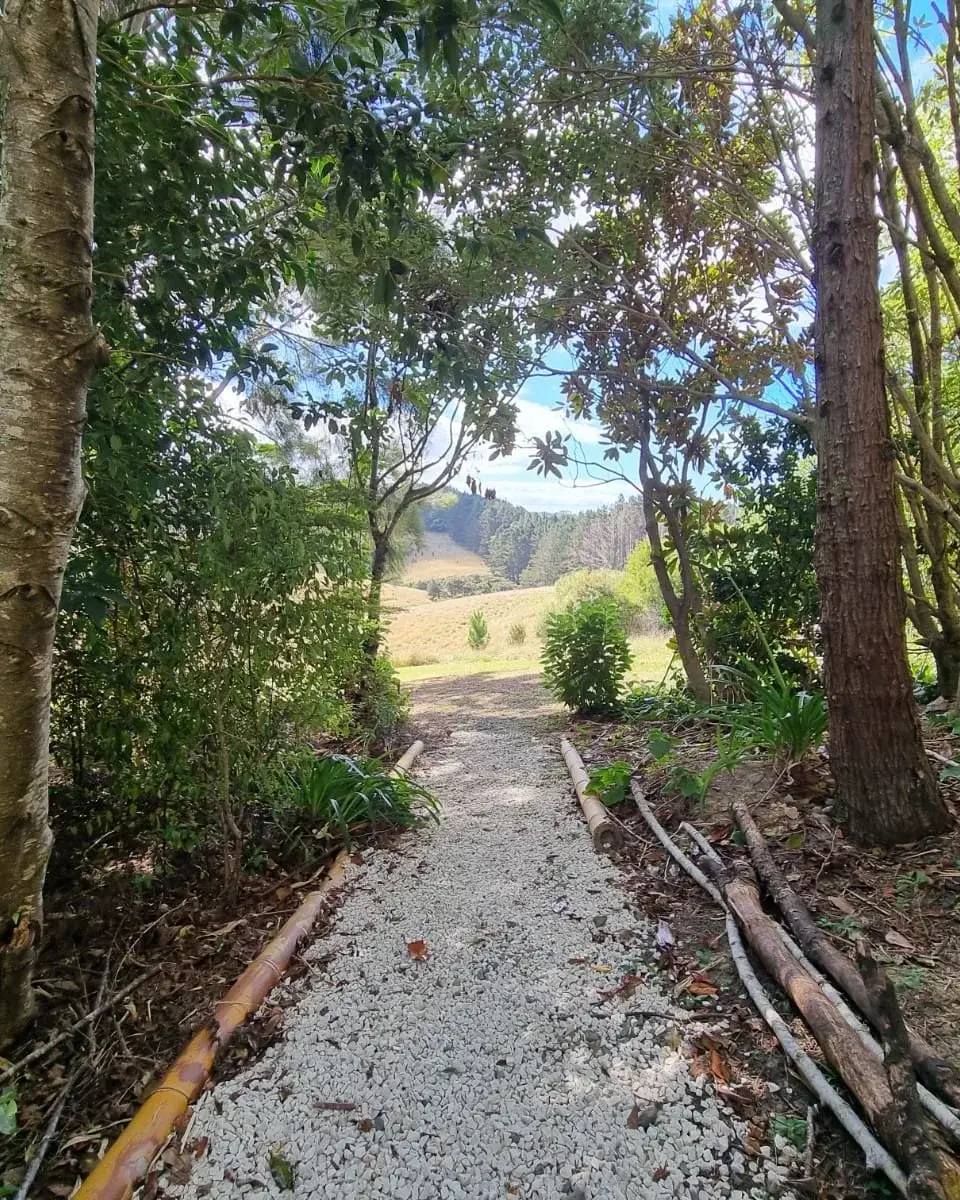 A gravel path through lush green trees leading to an open field at Keystone Lodge.